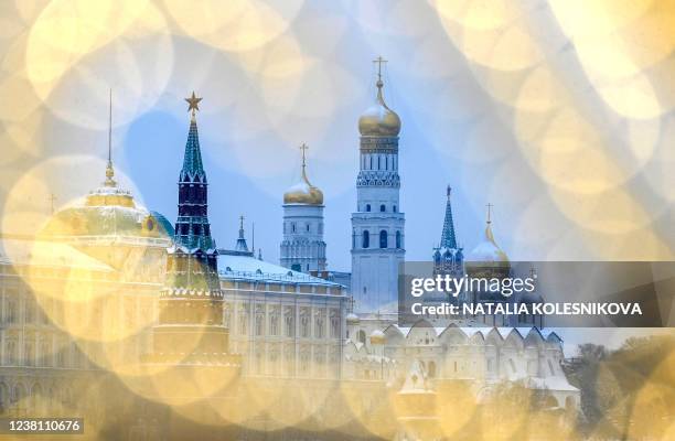 Picture taken in Moscow on February 1, 2022 shows Vodovzvodnaya tower and Ivan the Great bell tower in the Kremlin through illumination .