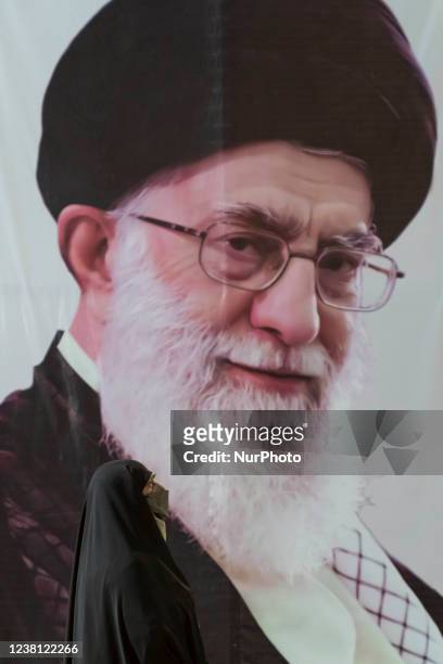An Iranian veiled woman stands in front of a portrait of Irans Supreme Leader Ayatollah Ali Khamenei while taking part in a ceremony to mark the 43rd...