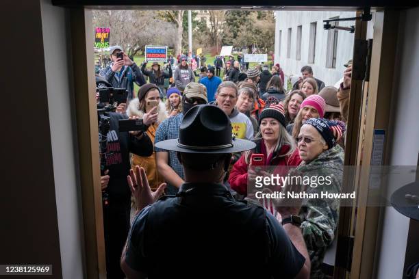 Attendees at a rally against vaccine and mask mandates argue with Oregon state troopers while trying to enter the state capitol on February 1, 2022...