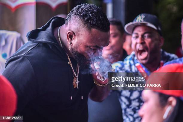 Dominican-US former Major League Baseball player David Ortiz smokes a cigar as he signs autographs for fans during a Caribbean Series baseball match...