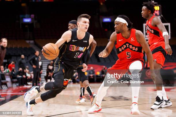 Tyler Herro of the Miami Heat dribbles by Precious Achiuwa of the Toronto Raptors during the second half of their NBA game at Scotiabank Arena on...