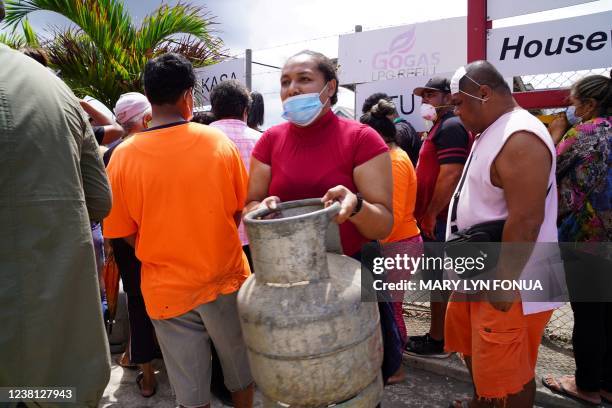 Woman carries a refilled gas container in the centre of the capital Nuku'alofa ahead of the country's first lockdown on February 2 after Covid-19 was...