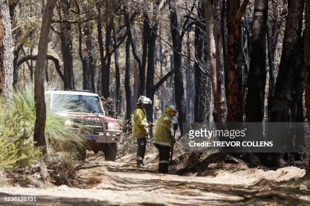 Firefighters conduct mop up operations in a smouldering forest after a bushfire that threatened homes was extinguished in the suburbs of Perth on...