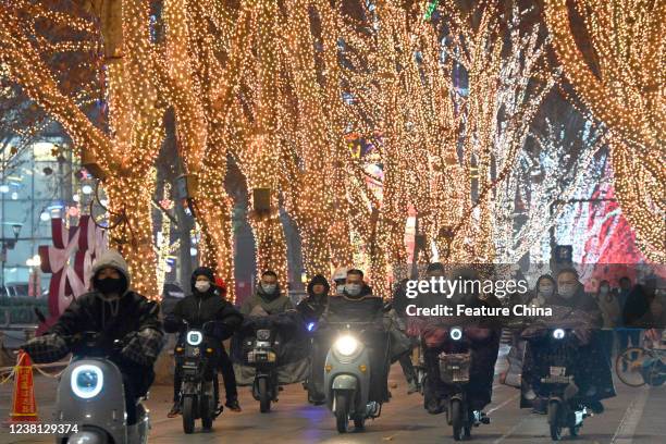 People on e-bikes pass a street with festive lights on the trees in Handan in north Chinas Hebei province Sunday, Jan. 30, 2022.