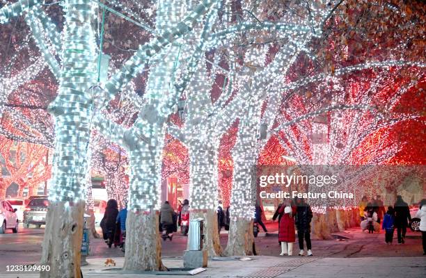 People walk in a street with festive lights on the trees in Handan in north Chinas Hebei province Sunday, Jan. 30, 2022.