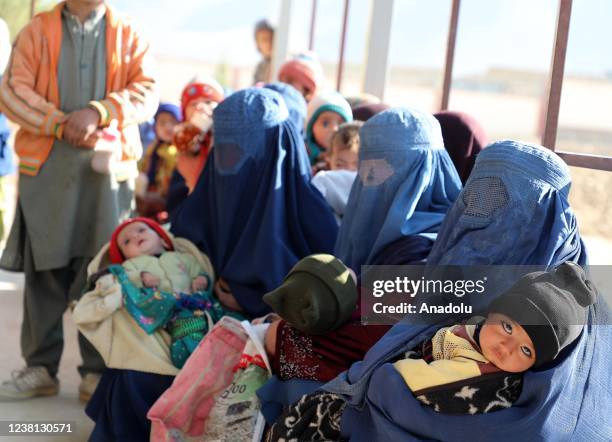 Afghan children are seen with their mothers in Kabul, Afghanistan on January 16, 2022. In Afghanistan, children cannot stand on their feet despite...