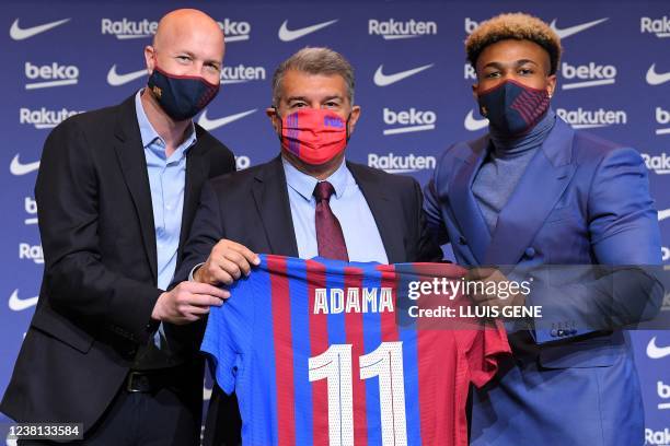 Barcelona's Spanish new player Adama Traore poses for pictures holding his jersey with Barcelona's Spanish sporting advisor Jordi Cruyff and...