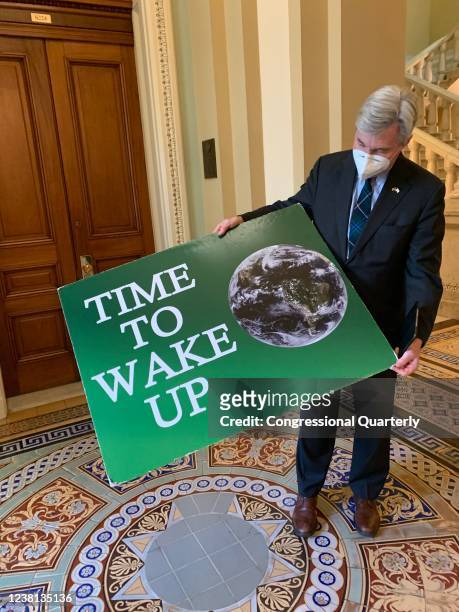 Sen. Sheldon Whitehouse shows off his Time to Wake Up poster on Wednesday, January 27 before retiring it, hopefully for good, he said. .
