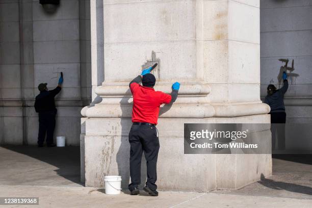 Workers use wire brushes to clean off swastikas that were drawn on the exterior of Union Station in Washington, D.C., on Wednesday, February 2, 2022....