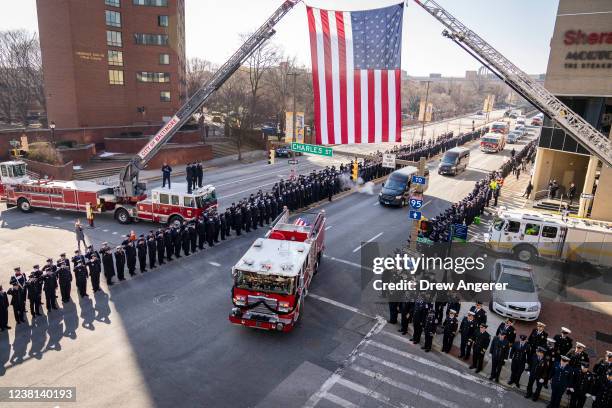 Firefighters salute as the funeral procession leaves the memorial service for three fallen Baltimore City Fire Department firefighters at the...