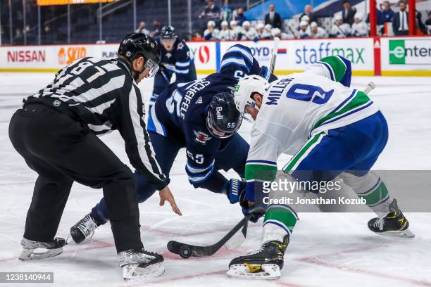 Mark Scheifele of the Winnipeg Jets and J.T. Miller of the Vancouver Canucks take a second period face-off at Canada Life Centre on January 27, 2022...