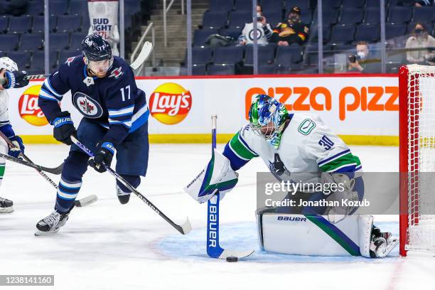 Goaltender Spencer Martin of the Vancouver Canucks stops the puck while Adam Lowry of the Winnipeg Jets looks on during second period action at...