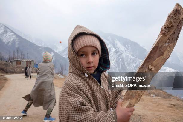 Boy looks on as he poses for a photo while playing cricket on a cloudy winter day on the outskirts of Srinagar.