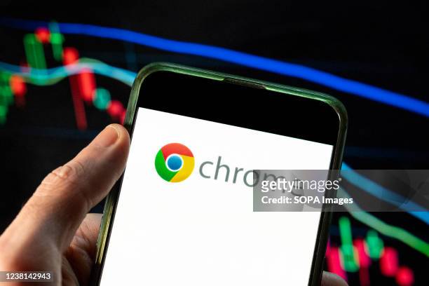 In this photo illustration the American web browser developed by Google, Chrome logo seen displayed on a smartphone with an economic stock exchange...