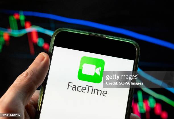 In this photo illustration the Apple video and audio calling service company, FaceTime logo seen displayed on a smartphone with an economic stock...