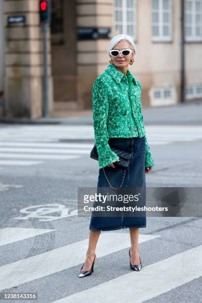 Influencer Grece Ghanem wearing a green jacket by Bottega Veneta, a blue denim midi skirt by Prada, white frame sunglasses by Bottega Veneta, gold...