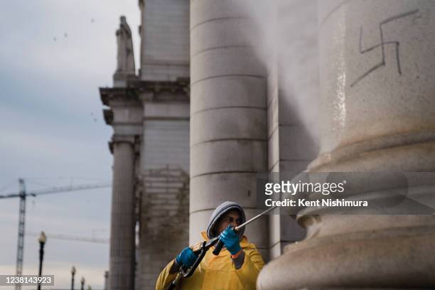 Juan Arias pressure washes a wall at Union Station to clean off swastikas and anti-Obama slogans that were drawn on the exterior of the building on...