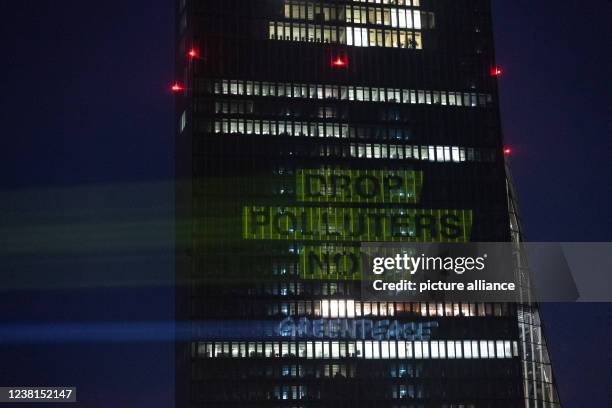 February 2022, Hessen, Frankfurt/Main: "Drop Polluters Now Greenpeace" is written on the facade of the European Central Bank during a Greenpeace...