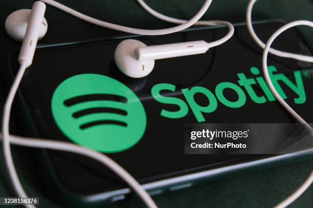 Spotify logo displayed on a phone screen and headphones are seen in this illustration photo taken in Krakow, Poland on February 3, 2022.