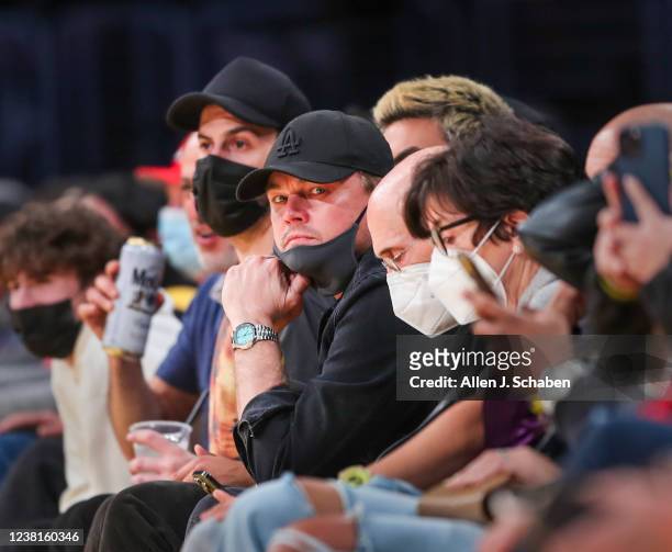 Los Angeles, CA Actor Leonardo DiCaprio, center in black hat with mask partly down, sits next to film producer Jeffrey Katzenberg, right of him with...