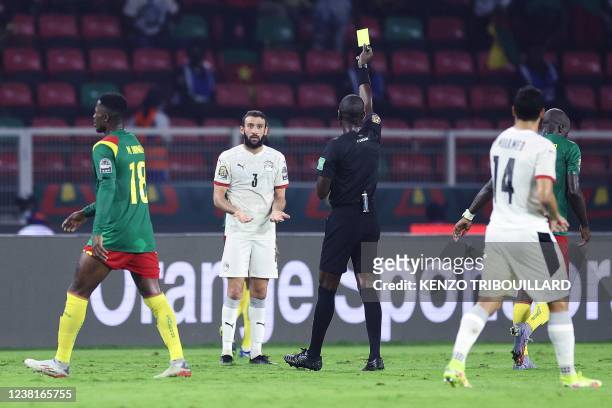 Egypt's defender Omar Kamal receives a yellow card from Gambian referee Bakary Gassama during the Africa Cup of Nations 2021 semi-final football...