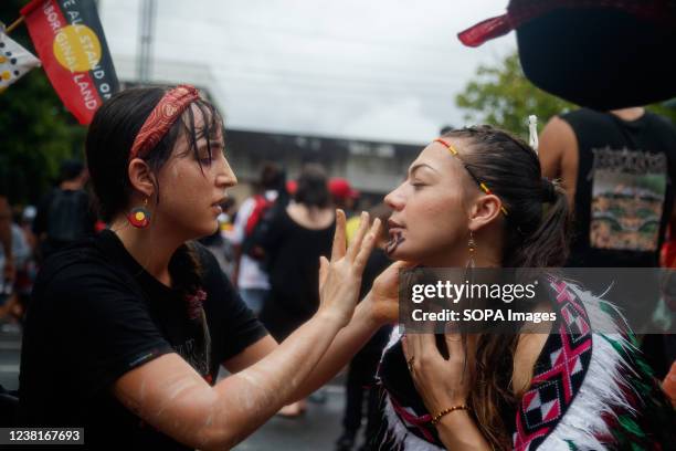 Members of the crowd apply traditional Aboriginal face paint during the march towards Musgrave Park. Protesters took to the streets of Brisbane,...