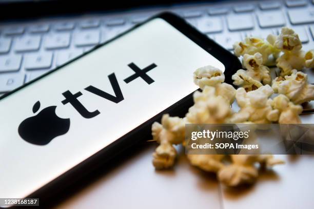 In this photo illustration a Apple TV logo seen displayed on a smartphone with popcorns and laptop keyboard in the background.