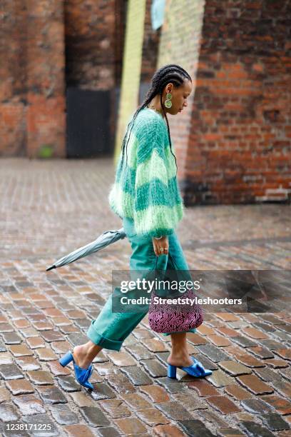 Fia Hamelijnck wearing a green knitted pullover by Knits by Dellie, green wide leg denim jeans pants by Baum und Pferdgarten, blue sandals with bows...