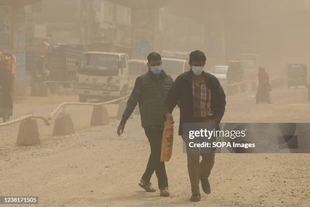 Men cross a dusty air heavily polluted road at Gazipur. Dust pollution has reached an alarming level at Gazipur in Dhaka due to brick production in...