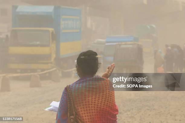 Woman crosses a dusty and heavily polluted road at Gazipur. Dust pollution has reached an alarming level at Gazipur in Dhaka due to brick production...