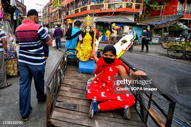 Girl sits on a rickshaw van taking an idol to her home for worshiping purposes. Basant Panchami or Vasant Panchami is a Hindu festival that...