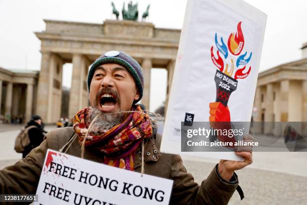 Dpatop - 04 February 2022, Berlin: An activist protests with posters during a vigil of the Society for Threatened Peoples on the occasion of the...