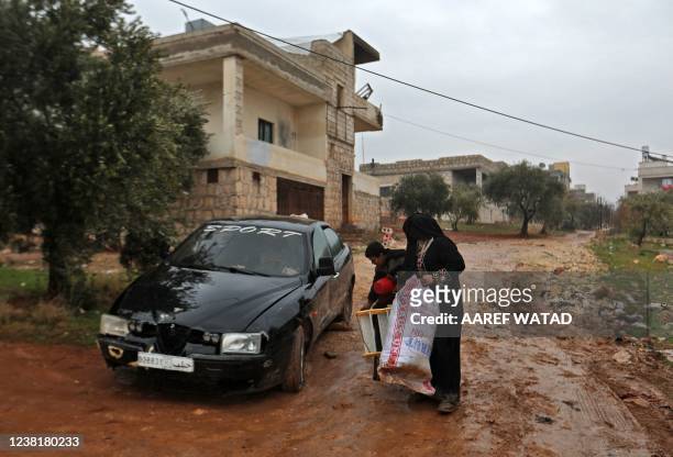 An impoverished Syrian woman and a child collect items near the house in which the leader of Islamic State group Amir Mohammed Said Abd al-Rahman...