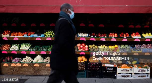 Pedestrian walks past a display of fruit and vegetables at a market in Walthamstow, east London on February 4, 2022. - The UK government on Thursday...