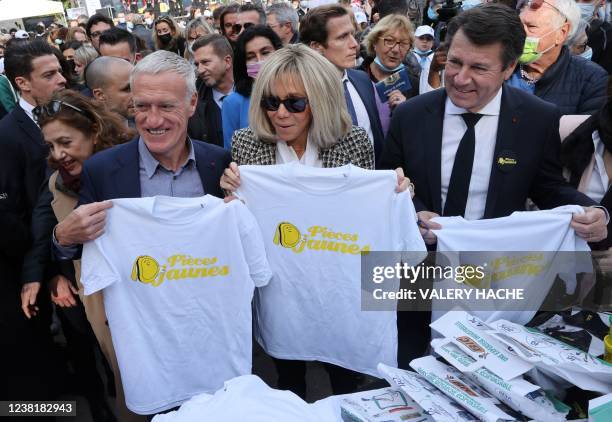 French president's wife Brigitte Macron holds a tee-shirt with France's head coach Didier Deschamps and French mayor of Nice Christian Estrosi during...