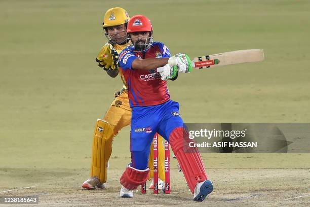 Karachi Kings' captain Babar Azam plays a shot as Peshawar Zalmi's wicketkeeper Kamran Akmal watches during the Pakistan Super League Twenty20...