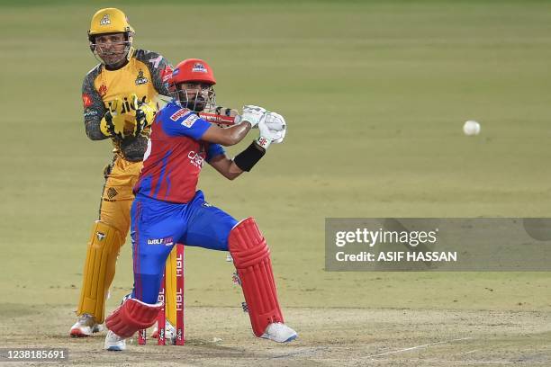 Karachi Kings' captain Babar Azam plays a shot as Peshawar Zalmi's wicketkeeper Kamran Akmal watches during the Pakistan Super League Twenty20...