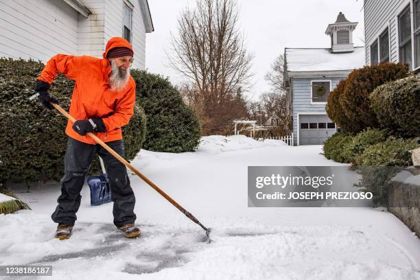 Man breaks up ice and sleet on his driveway during a winter storm in Concord, New Hampshire on February 4, 2022. - The winter storm stretched from...