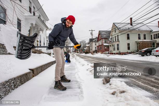 Father and son shovel sleet from the sidewalk during a winter storm in Concord, New Hampshire on February 4, 2022. - The winter storm stretched from...