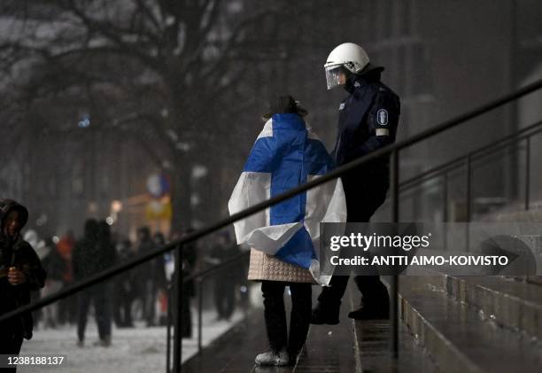 Police officer talks with a protester wearing Finland's national flag in front of the Parliament Building in central Helsinki, Finland, on February 4...