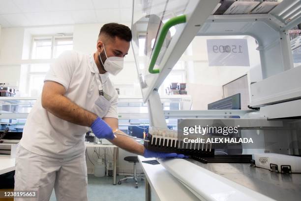 An employee in the laboratory of the LifeBrain company puts coronavirus PCR gargle test samples into an analysis device in Vienna on February 1,...