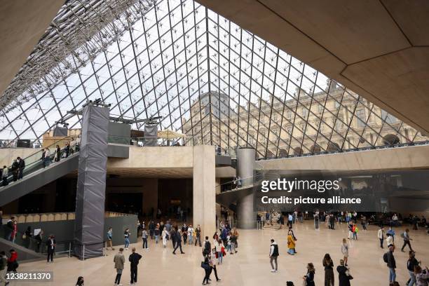 October 2021, France, Paris: Visitors walk through the glass pyramid in the Louvre. It represents the entrance for visitors and is a kind of center...