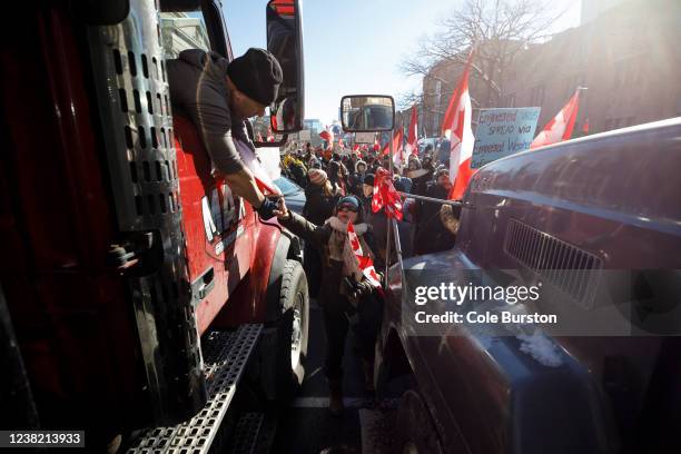 Supporter shakes the hand of a trucker as a convoy of truckers arrives to a police blockade on February 5, 2022 in Toronto, Canada. A convoy of...