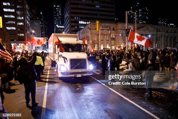 Supporters wave flags as a convoy of trucks leave from Bloor St. And University Ave. On February 5, 2022 in Toronto, Canada. A convoy of truckers and...