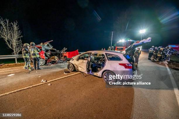 February 2022, North Rhine-Westphalia, Gummersbach: Firefighters stand at the scene of the accident.In a car accident on a country road near...