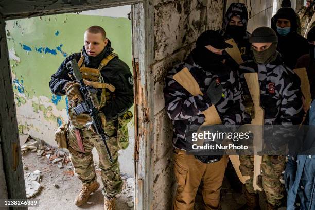 Member of the Azov batallion, left, with some civilian volunteers for the Territorial Defense Brigades of Kiev with wooden training rifles during a...