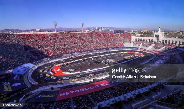 Los Angeles, CA With a view of downtown Los Angeles and the snow-capped mountains in the background, NASCAR racers circle the quarter-mile track...