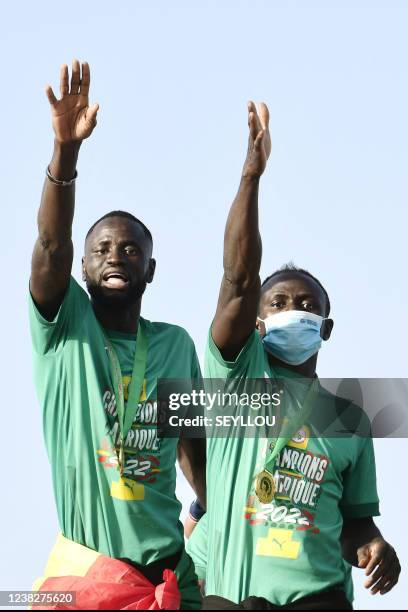 Senegal midfielder Cheikhou Kouyate and Sengal striker Sadio Mane greet supporters in Dakar on February 7, 2022 from atop of a bus on the tarmac of...