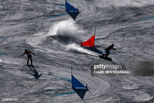 Austria's Julia Dujmovits and Switzerland's Patrizia Kummer compete in the snowboard women's parallel giant slalom 1/8 finals during the Beijing 2022...