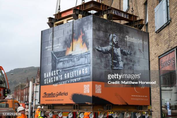 Workers remove the Season's Greetings Banksy artwork from a commercial unit on February 8, 2022 in Port Talbot, Wales. The Port Talbot Banksy,...